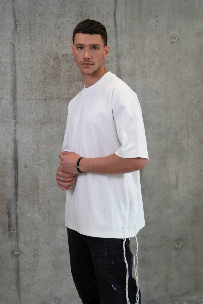 חולצת ציצית לבנה דגם TRUE IDENTITY על דוגמן בצילומי סטודיו - צד רקע בטון