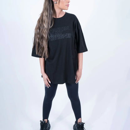 טישרט שחורה הדפס שחור "HASHEM IS MY DESIGNER" על הדוגמנית בצילומי סטודיו - פרונט